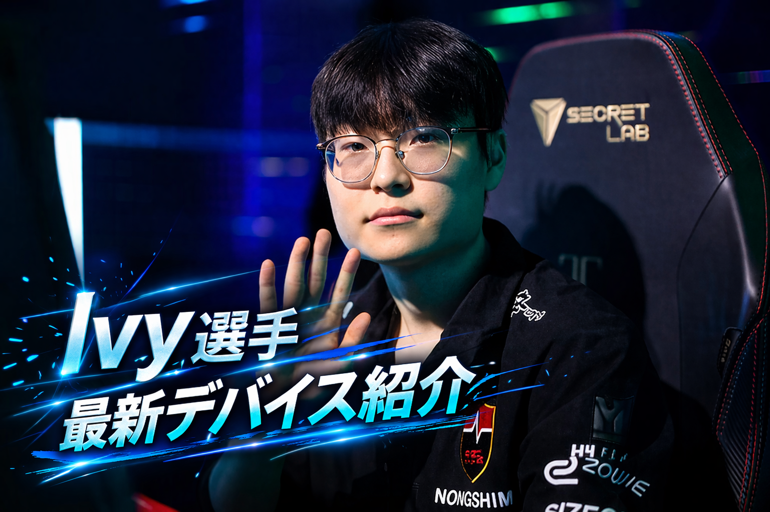 VALORANTプロゲーマー、NS Ivy選手の使用デバイス・設定紹介のサムネイル画像。 NS（Nongshim RedForce）のユニフォーム（NONGSHIM、ZOWIEなどのロゴ入り）とメガネを着用したIvy選手が、Secretlabのゲーミングチェアの前で正面を向き、左手で手を振っているポートレート。 画像左側には、青い光のラインと文字（「Ivy選手」、「最新デバイス紹介」）が、エフェクトと共に配置されている。背景は青と緑のゲーミングスタジオのライティング。